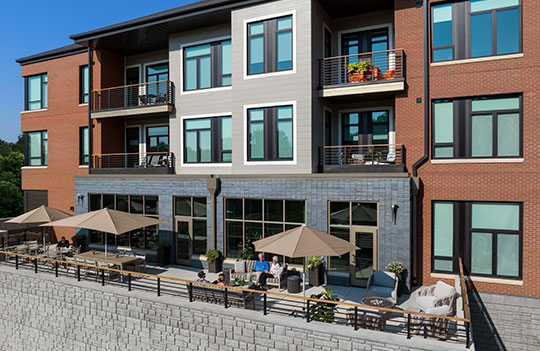 Outdoor patio area and building façade with people sitting on patio furniture.