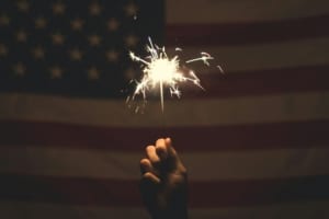Someone holding a sparkler up to an American flag for 4th of July.