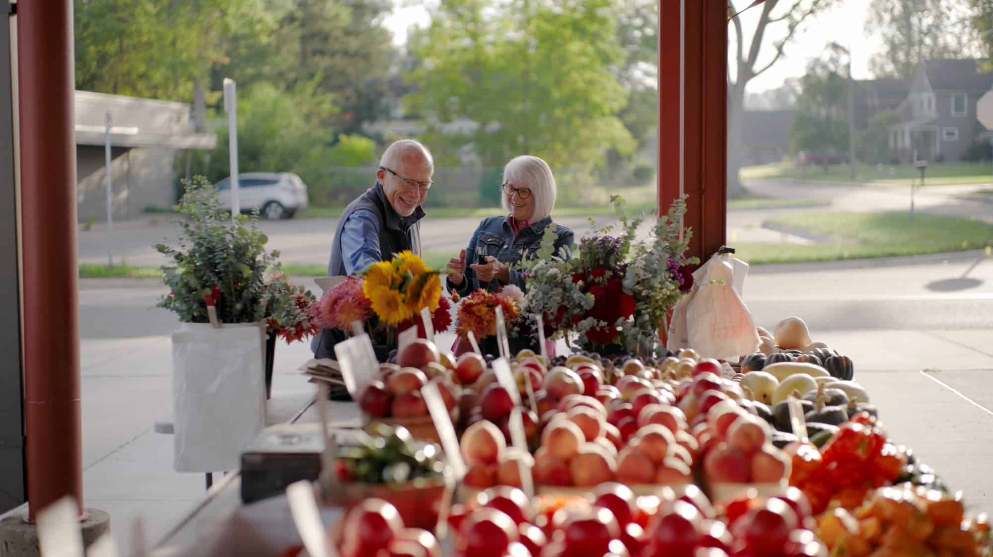 A senior man and senior woman looking at flowers found at the Fresh on Q in TexasTownship