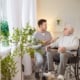 Senior man in wheelchair talking to young man in scrubs.