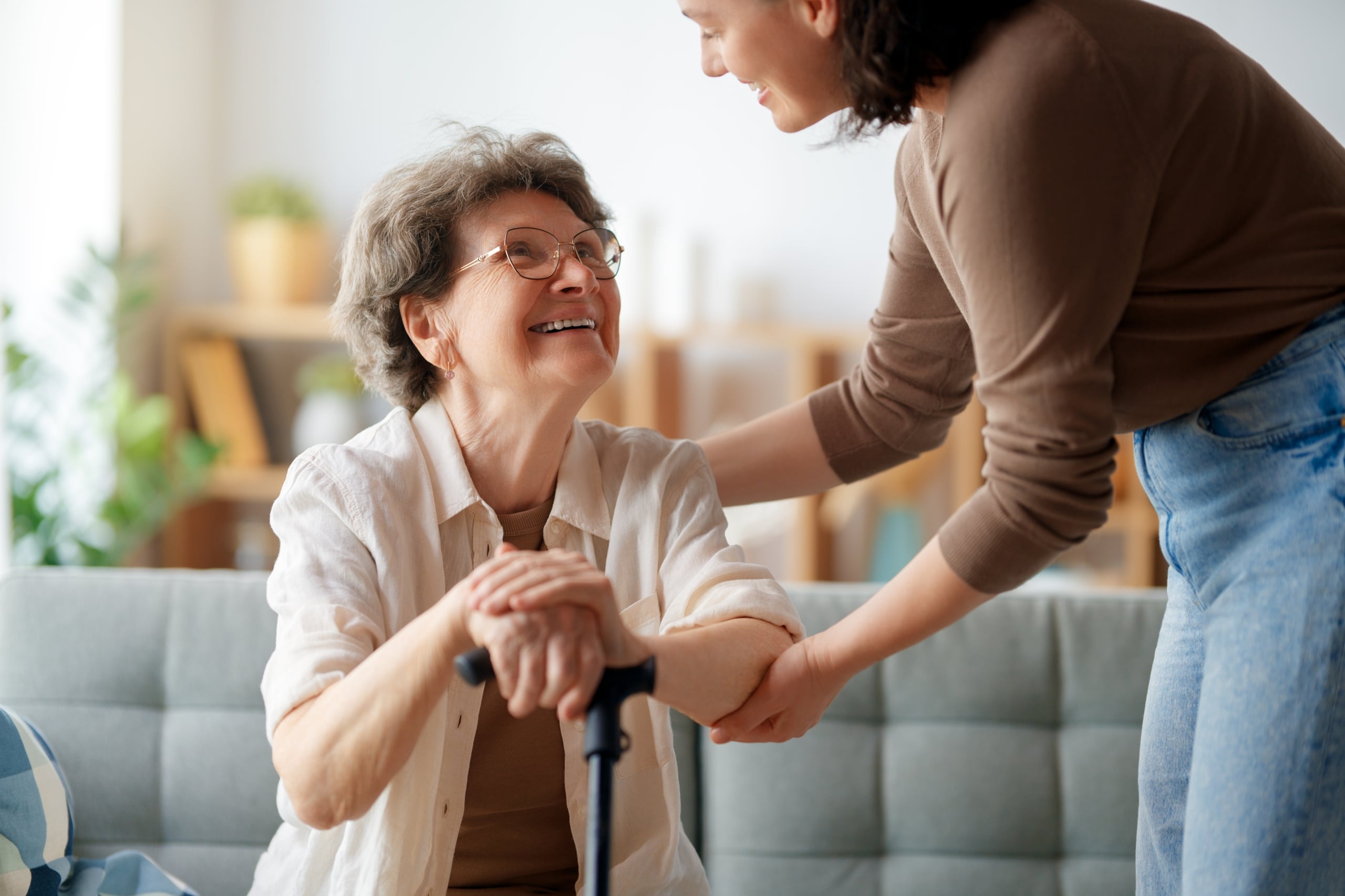 Happy senior woman looking up to another woman giving her assistance.