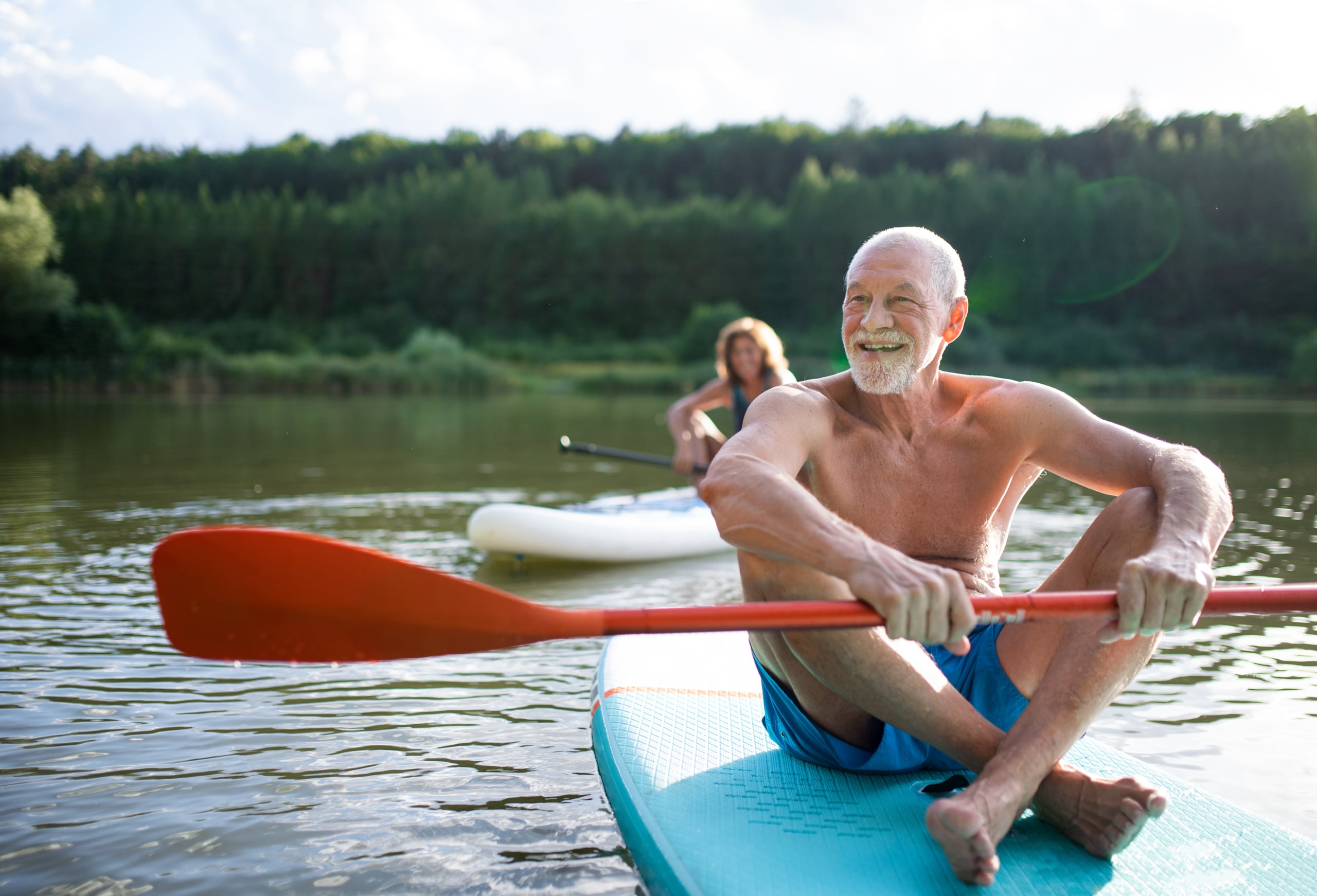 happy senior couple enjoy rides on paddleboards and kayaks