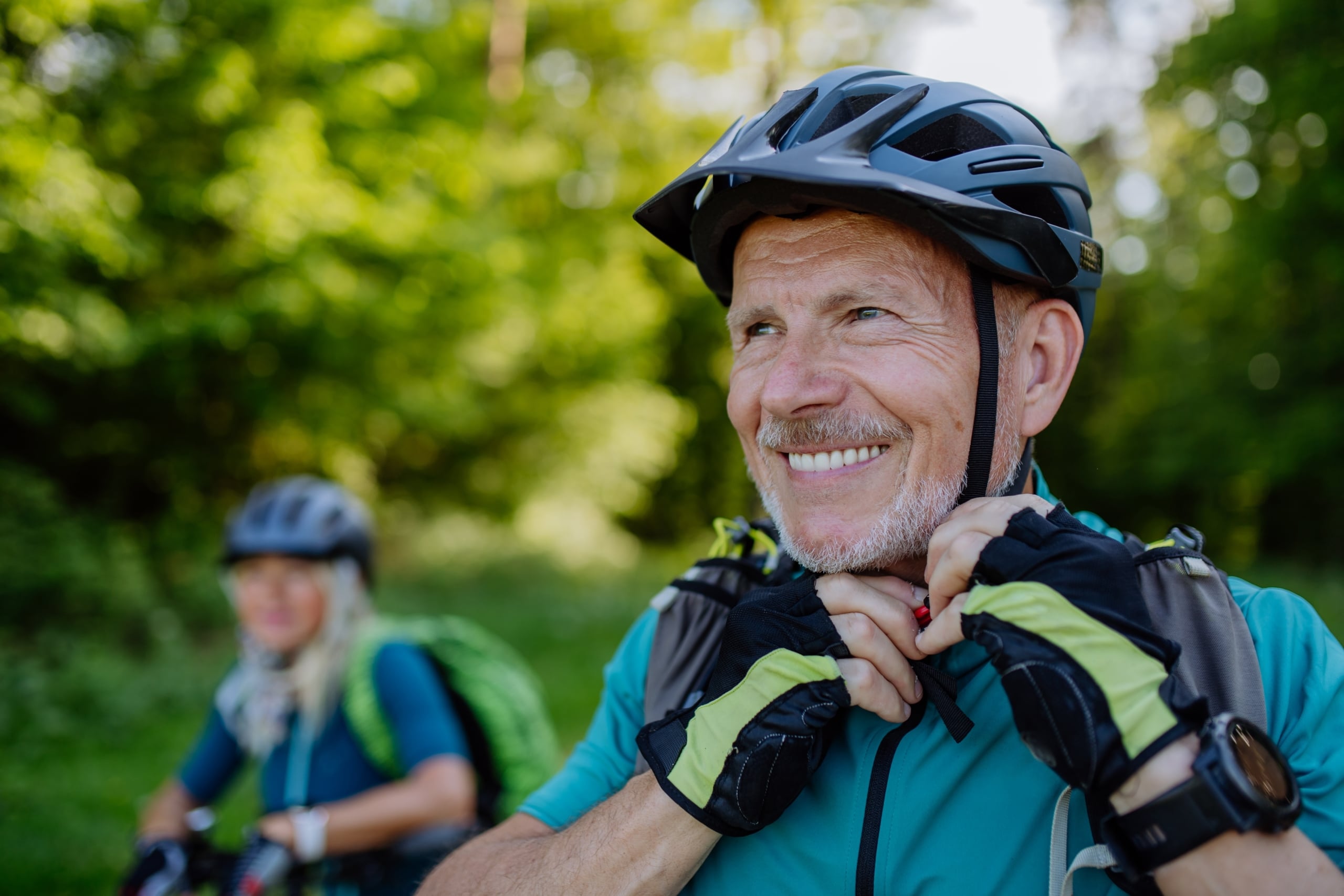 happy senior man buckles his bike helmet